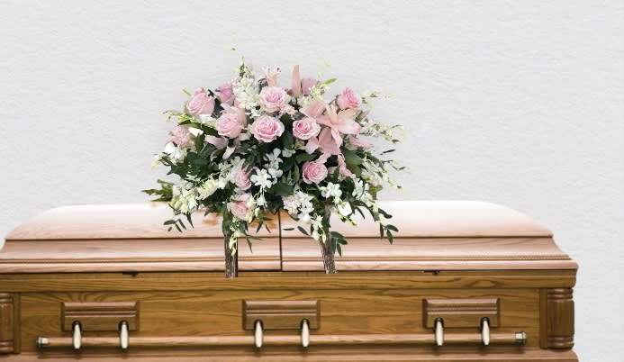 Pink and white floral spray on a wooden casket