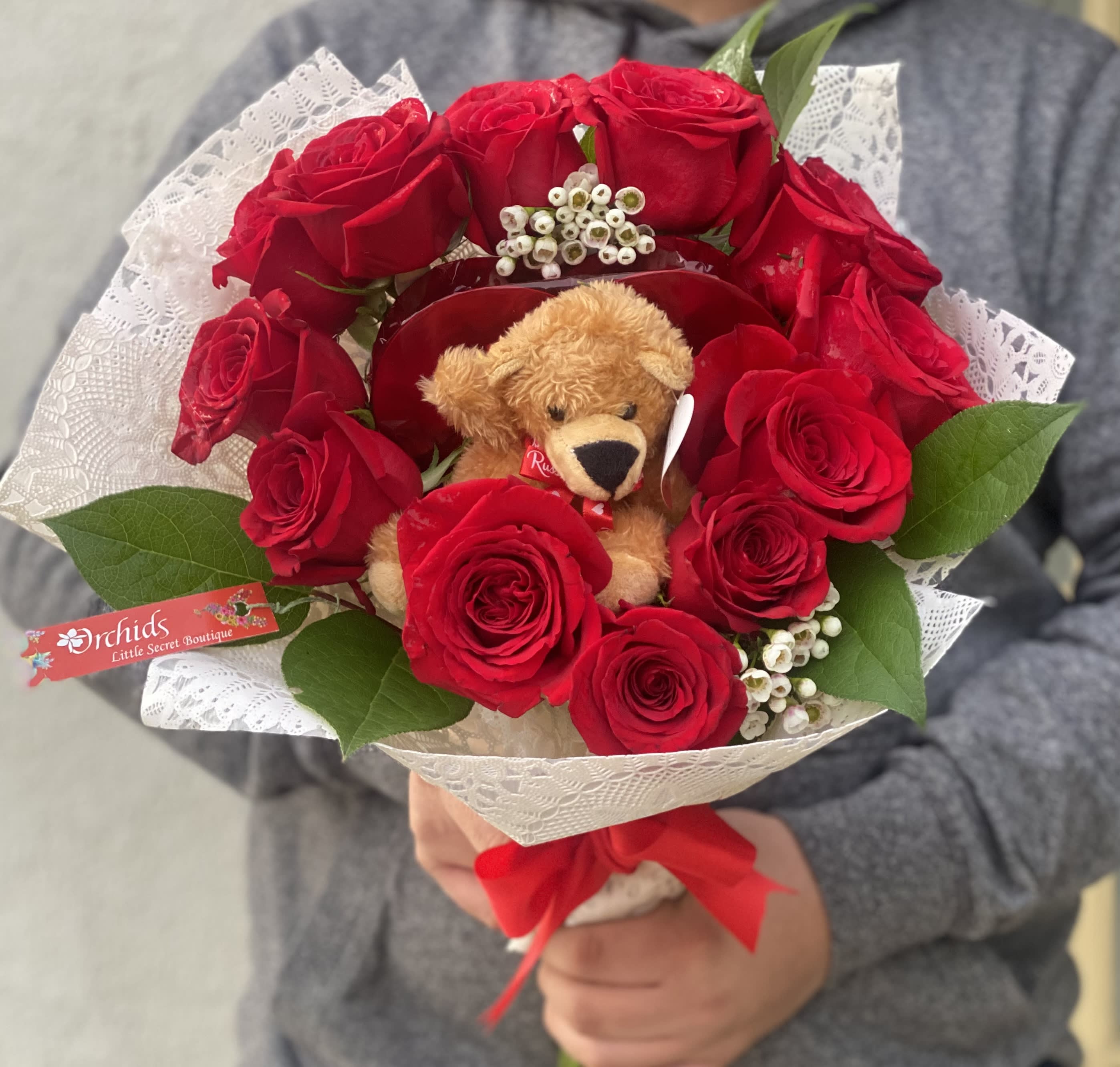 Bouquet of red roses with a teddy bear and white lace wrap