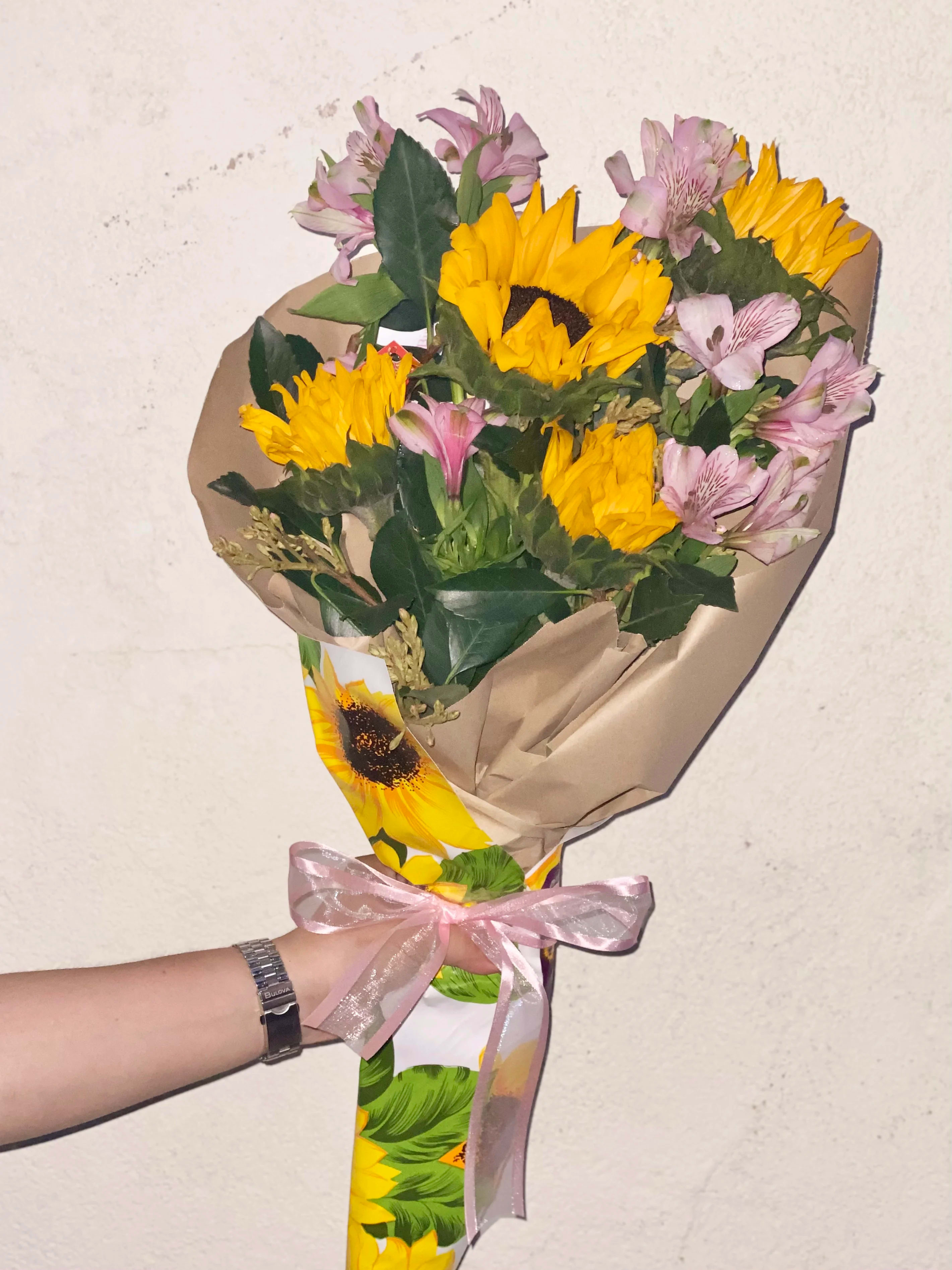Bouquet of yellow sunflowers and pink alstroemeria wrapped in paper