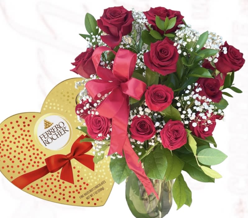 Bouquet of red roses in a glass vase beside a heart-shaped chocolate box