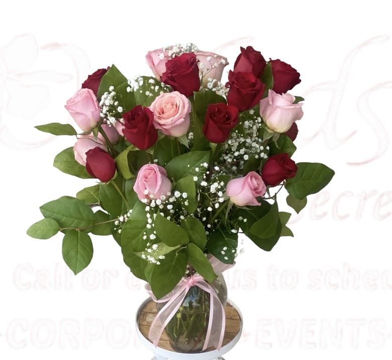 Bouquet of red and pink roses in a glass vase with a pink ribbon