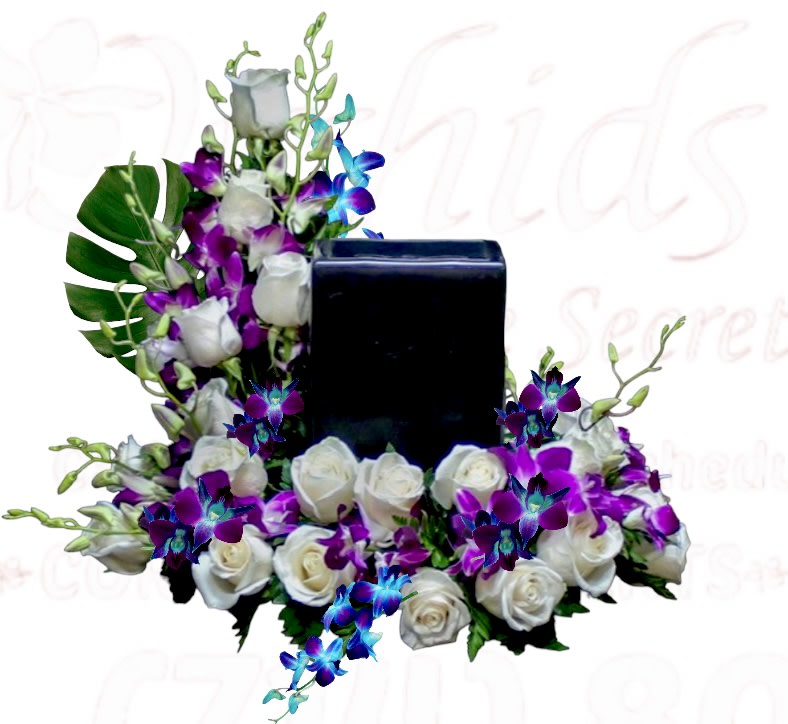 White roses and purple orchids arranged around a black rectangular vase