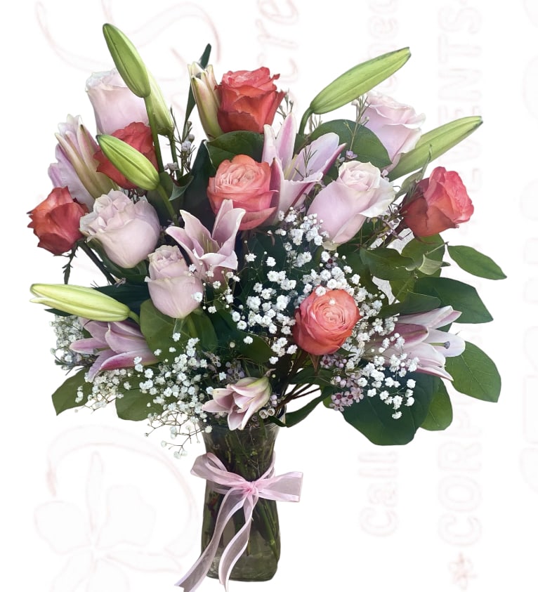 Bouquet of pink roses and lilies in a glass vase with a ribbon