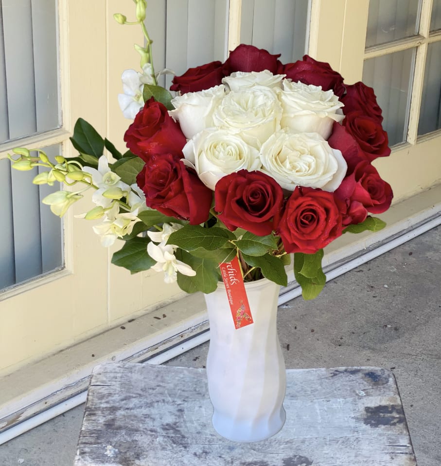 Red and white roses arranged in a white vase