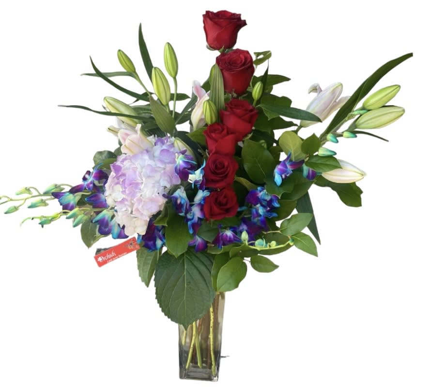 Red roses, lilies, and lavender hydrangea in a glass vase
