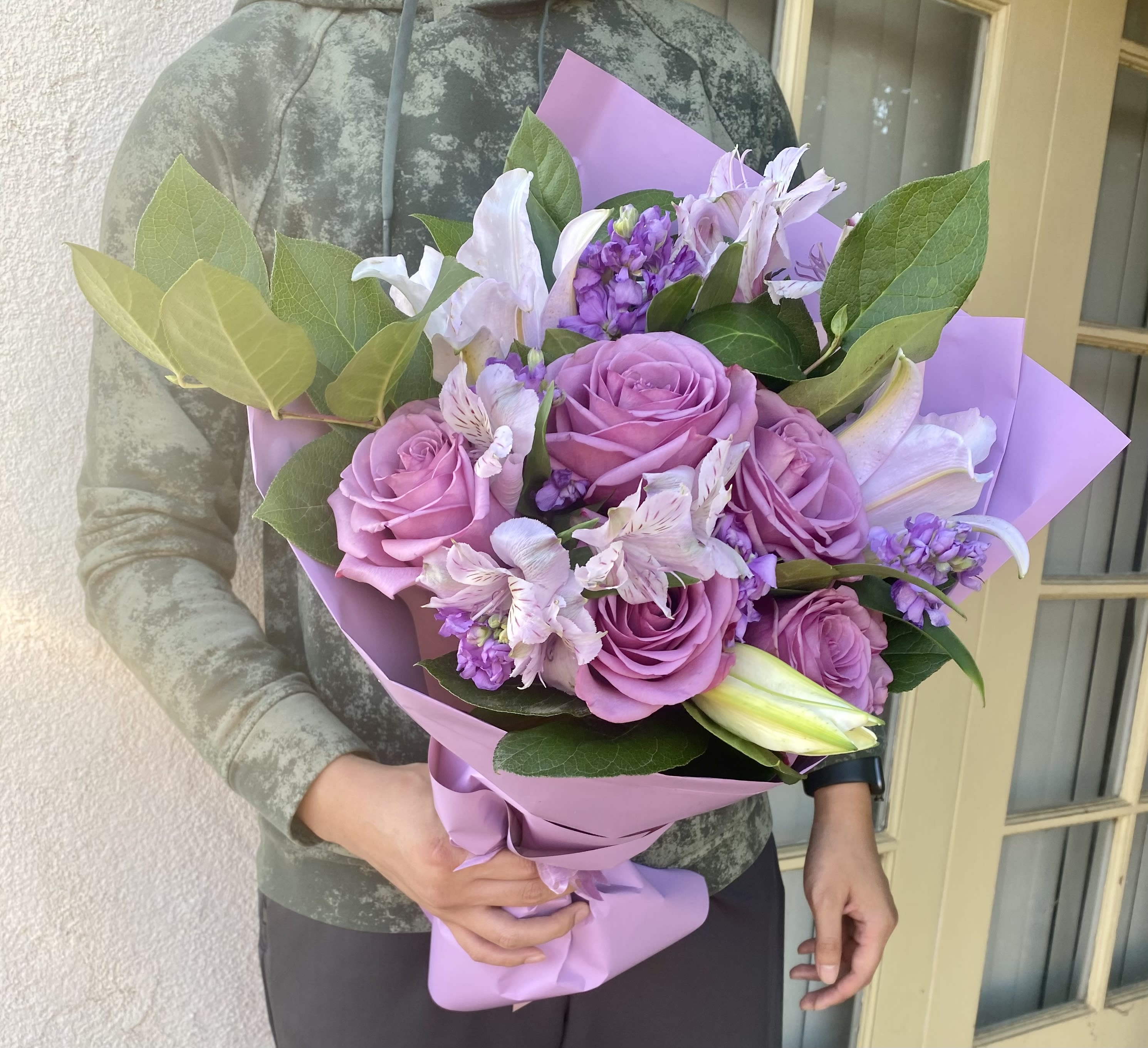 Bouquet of pink roses and lilies wrapped in lavender paper