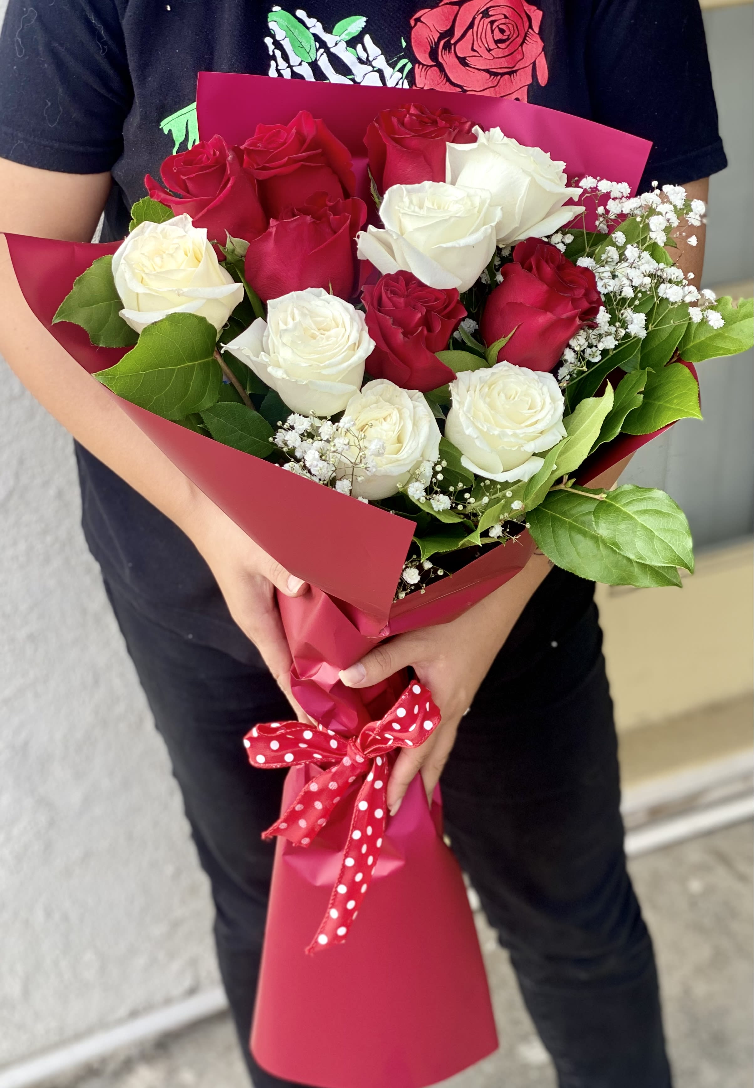 Bouquet of red and white roses wrapped in pink paper with a polka-dot ribbon
