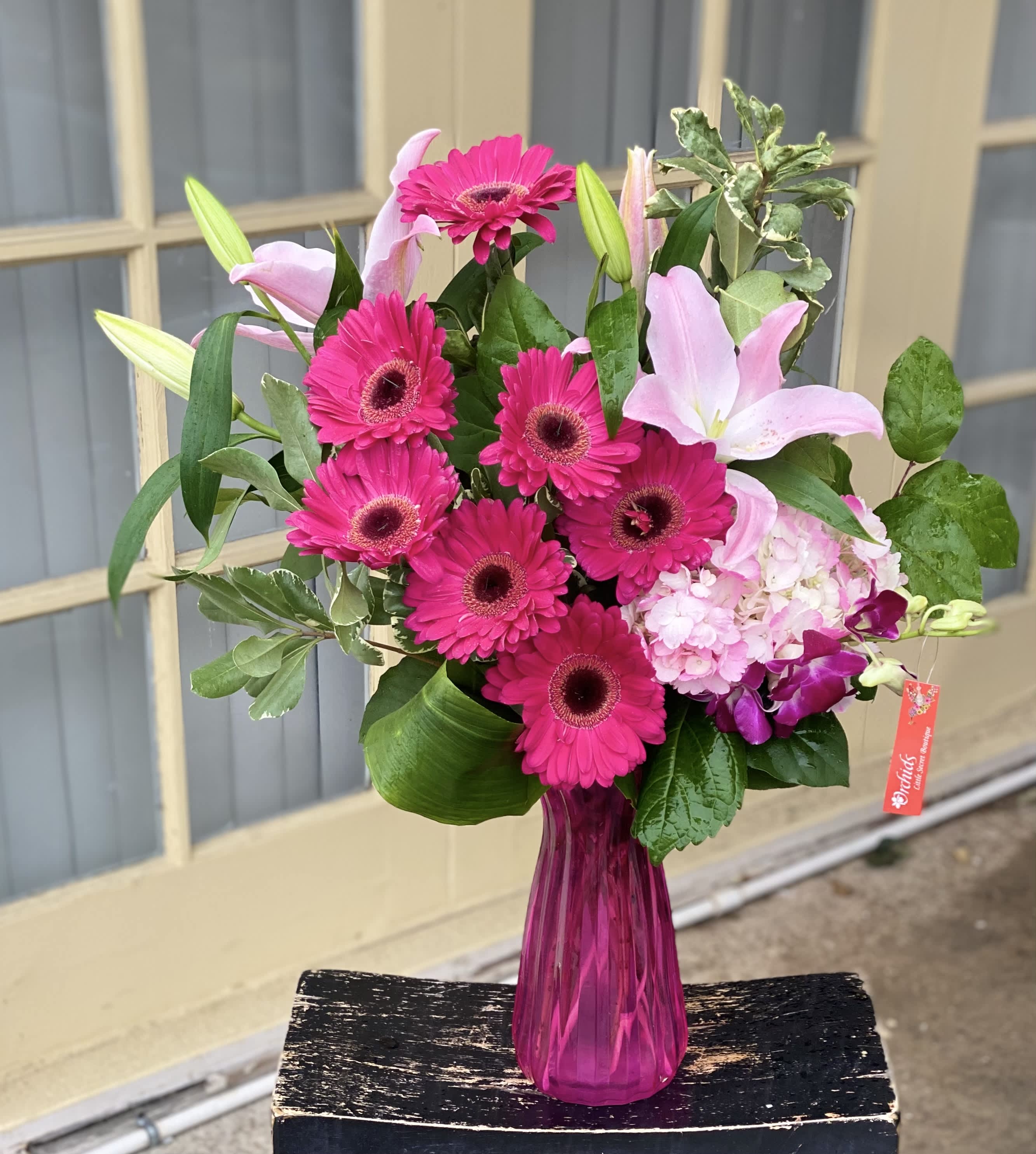 Pink gerberas and lilies in a magenta glass vase