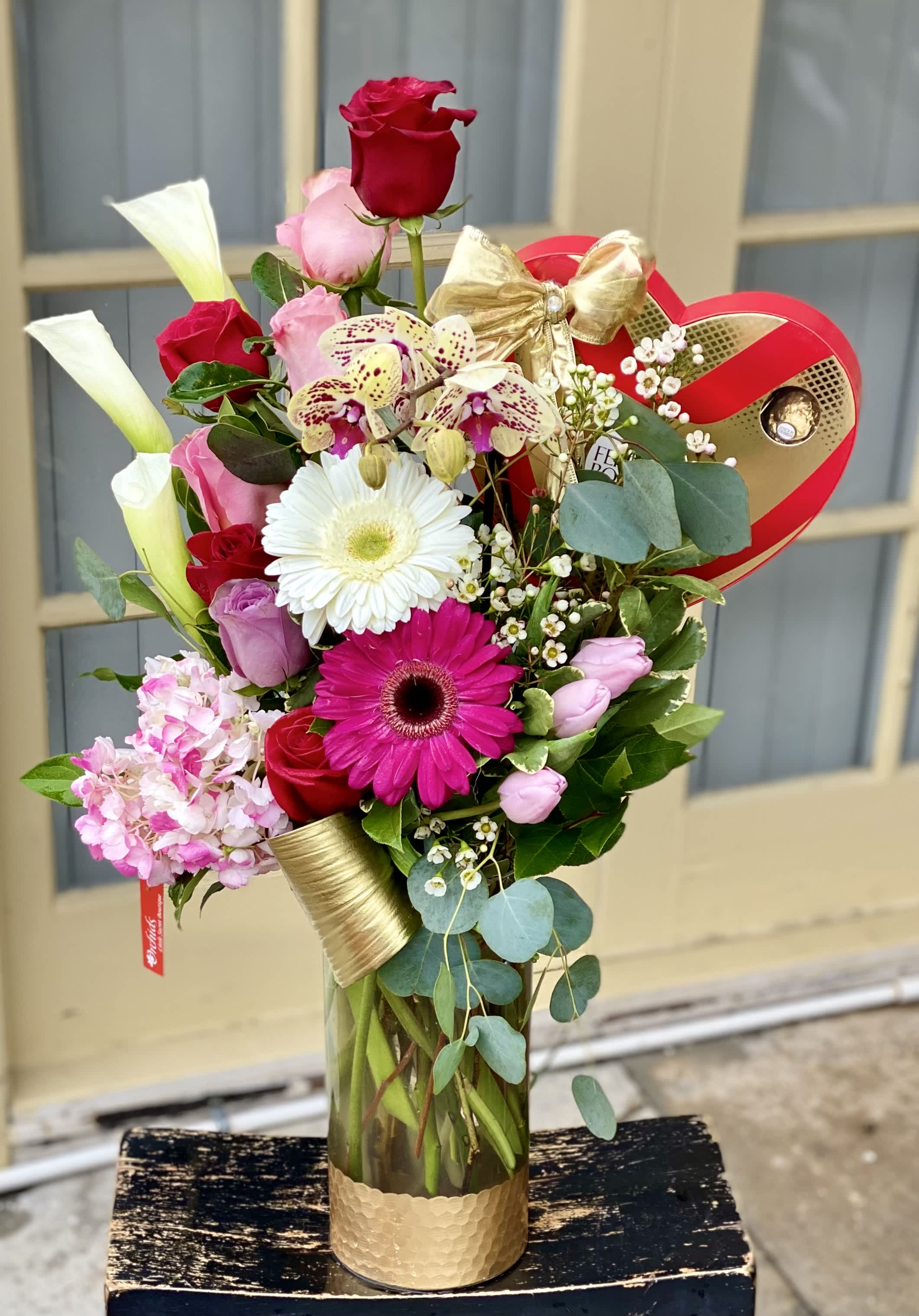 Mixed bouquet in a glass vase with roses, gerbera daisies, orchids, and calla lilies