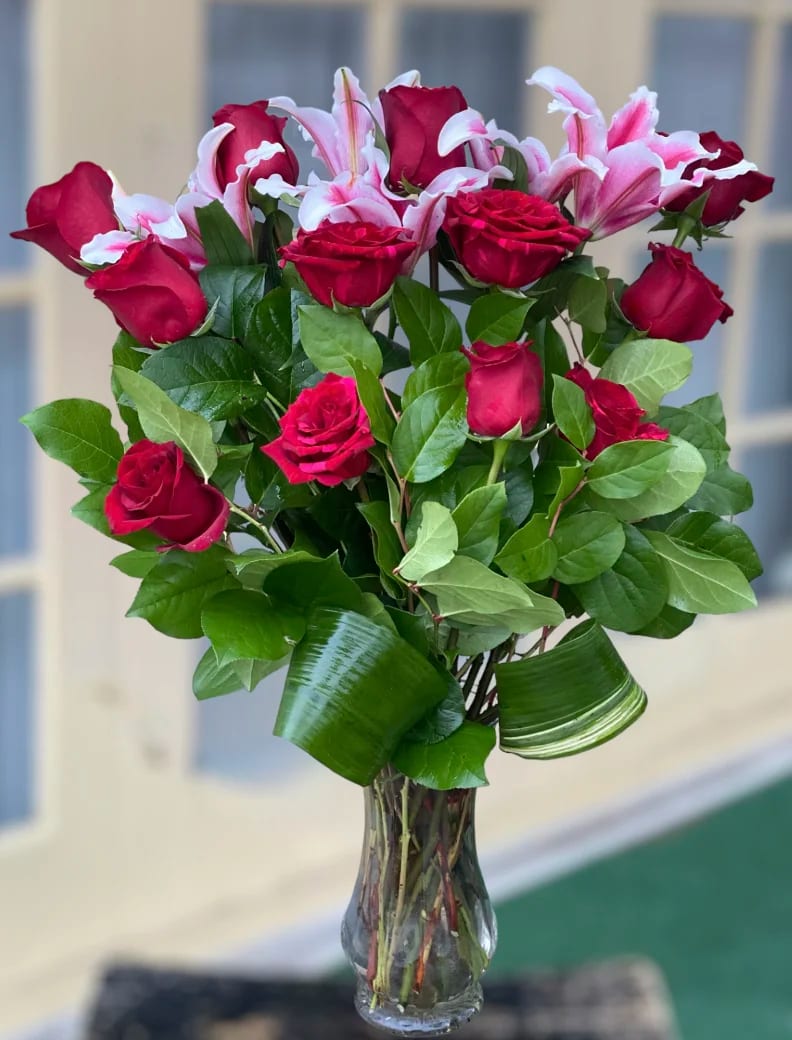 Bouquet of red roses and pink lilies in a clear glass vase