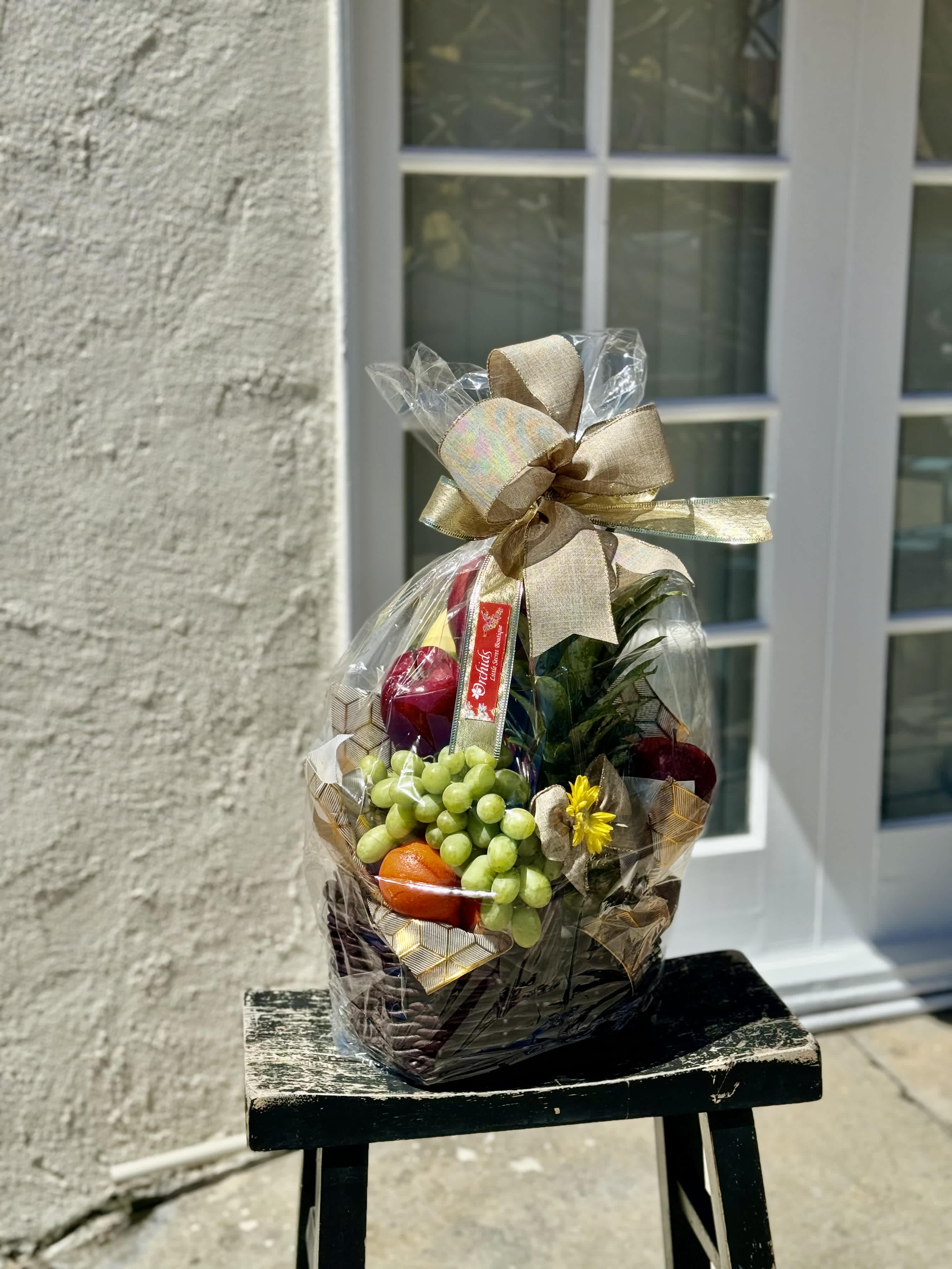 Gift basket with fruit and a ribbon bow wrapped in clear cellophane
