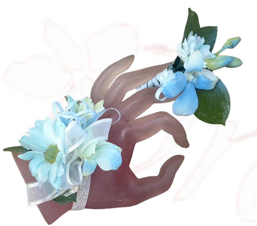 Two blue floral wrist corsages with ribbon on a hand display