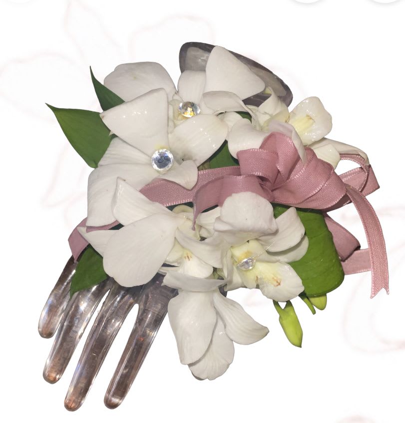 White orchid corsage with pink ribbon and jeweled accents on a clear comb