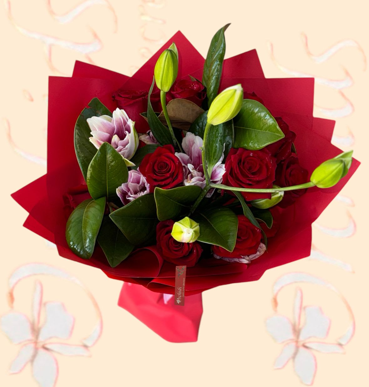 Bouquet of red roses and pale lilies wrapped in red paper