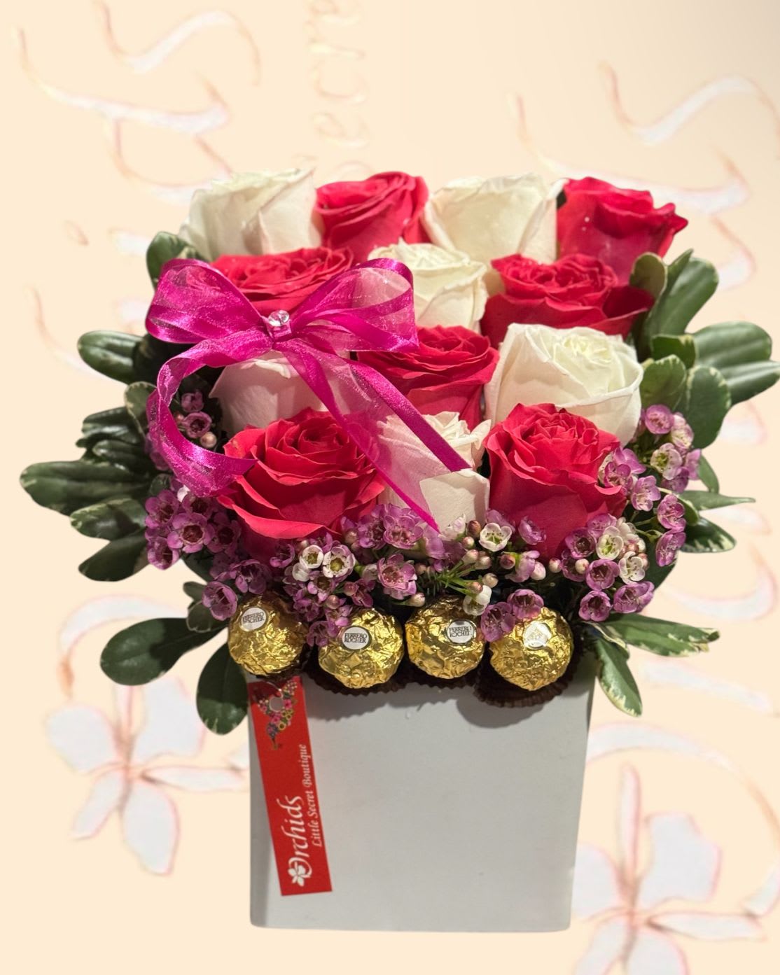 Pink and white roses in a square box with a ribbon and chocolates