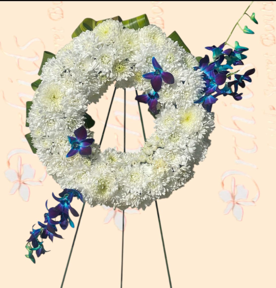White chrysanthemum wreath with blue-purple orchid accents on a stand