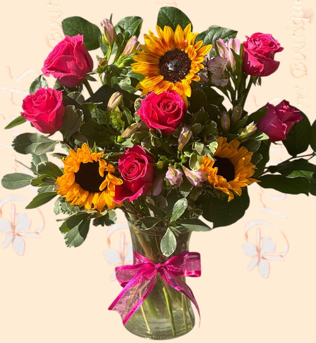 Bouquet of pink roses and sunflowers in a glass vase with a pink ribbon