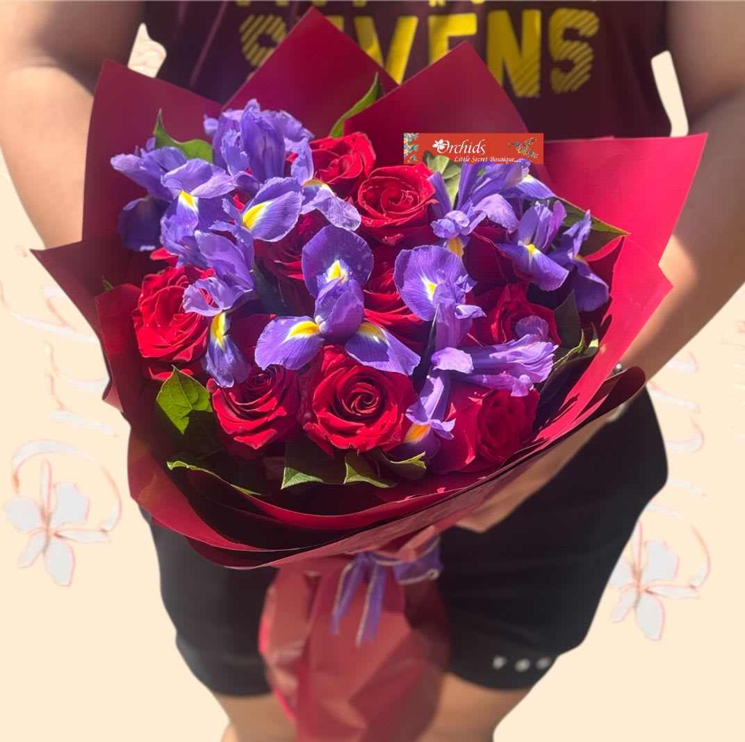 Bouquet of red roses and purple irises wrapped in burgundy paper