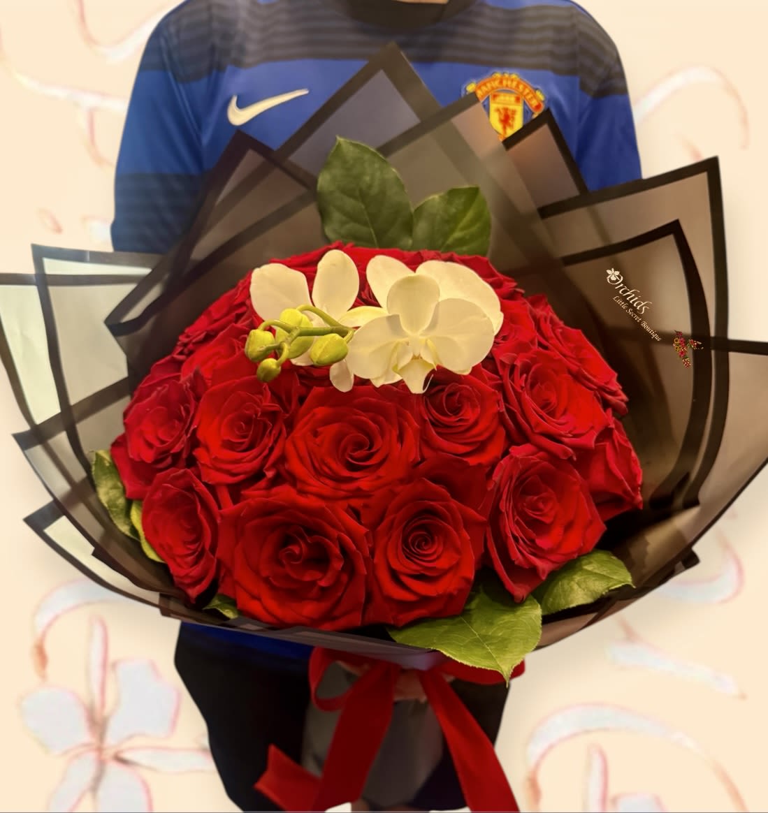 Bouquet of red roses with white orchids wrapped in dark paper