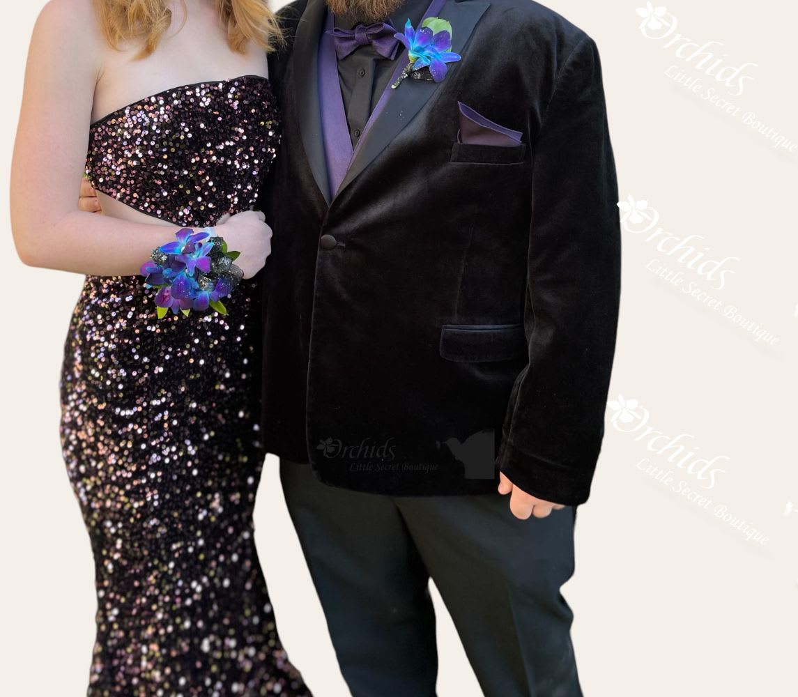 Formal couple wearing matching purple floral wrist corsages and boutonniere