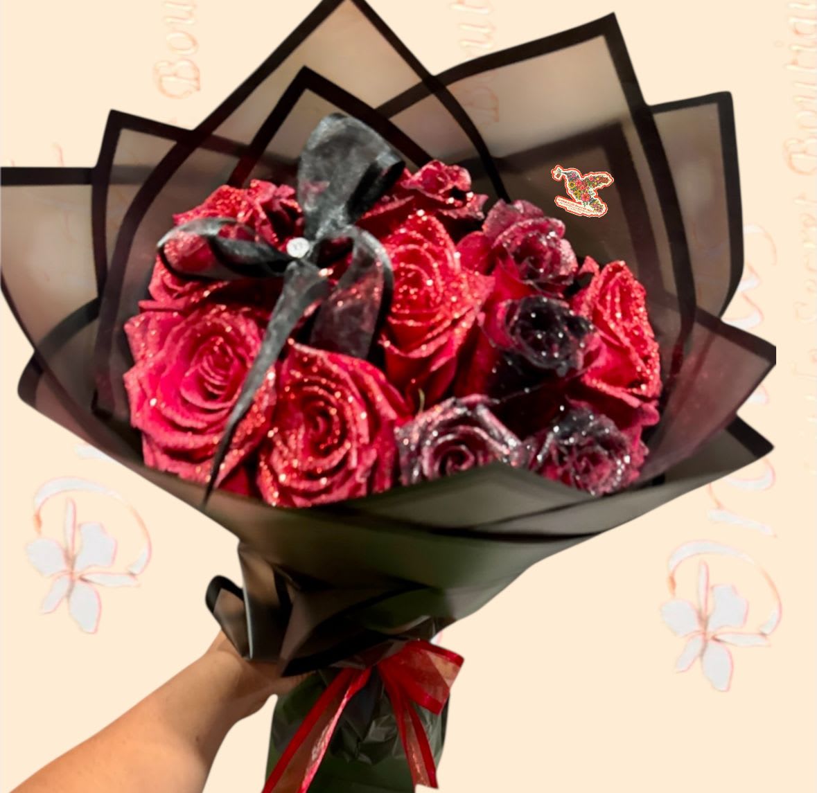 Bouquet of glittery red roses wrapped in black paper with a ribbon