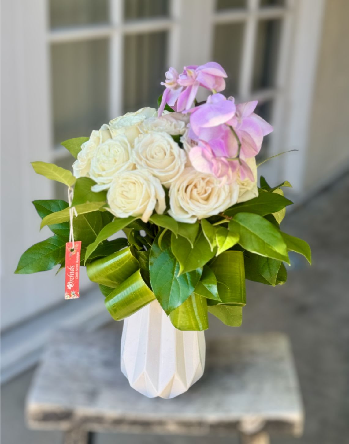 White roses and pink orchids in a white vase