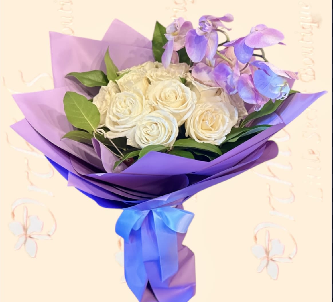 Bouquet of white roses and purple orchids wrapped in lavender paper