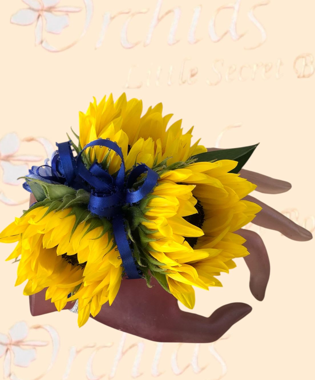 Handheld bouquet of bright yellow sunflowers tied with a blue ribbon