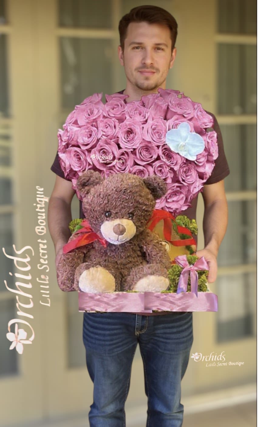Heart-shaped pink rose arrangement with a teddy bear and ribbon accents