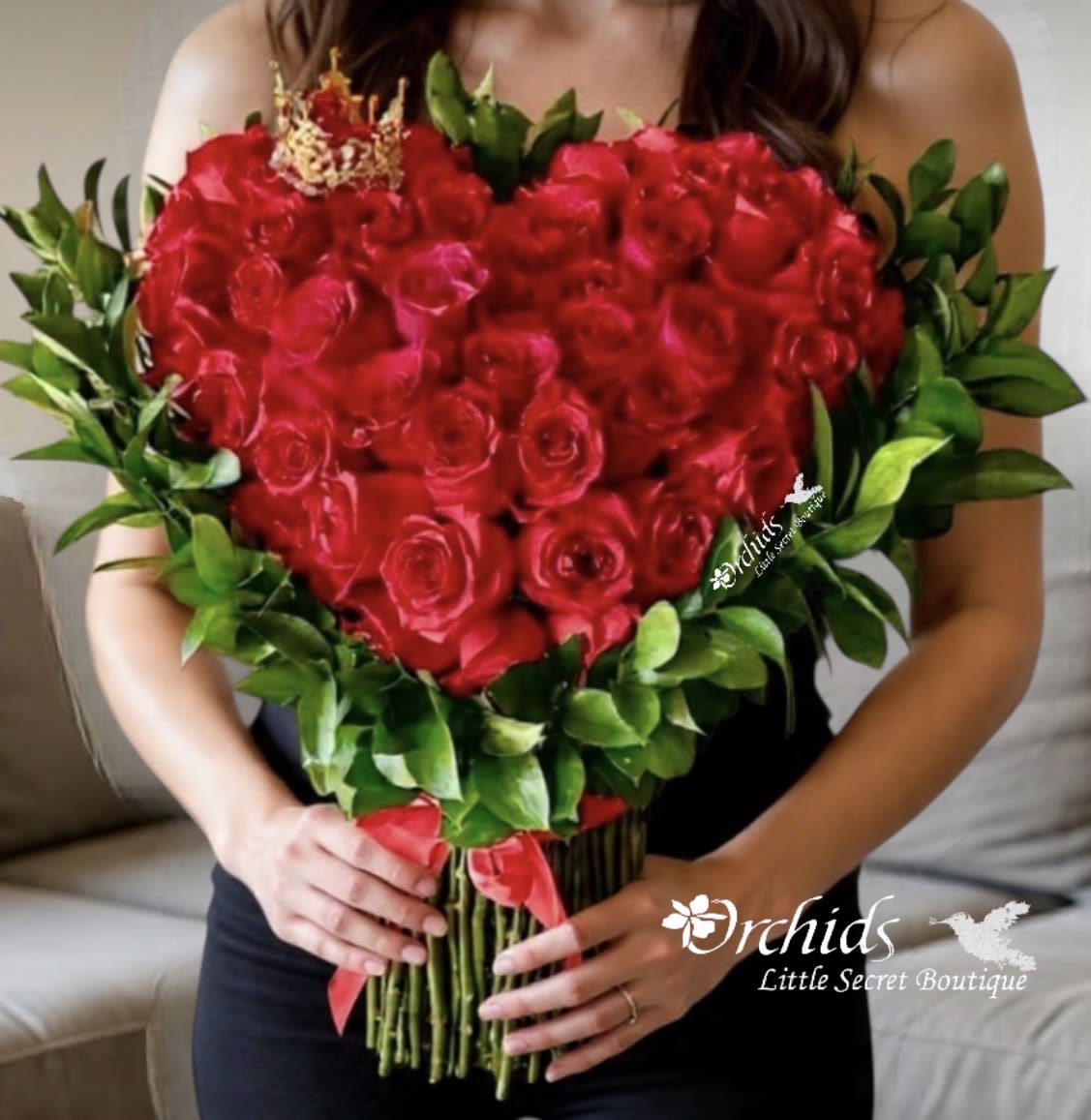 Heart-shaped bouquet of red roses with green foliage and a red ribbon