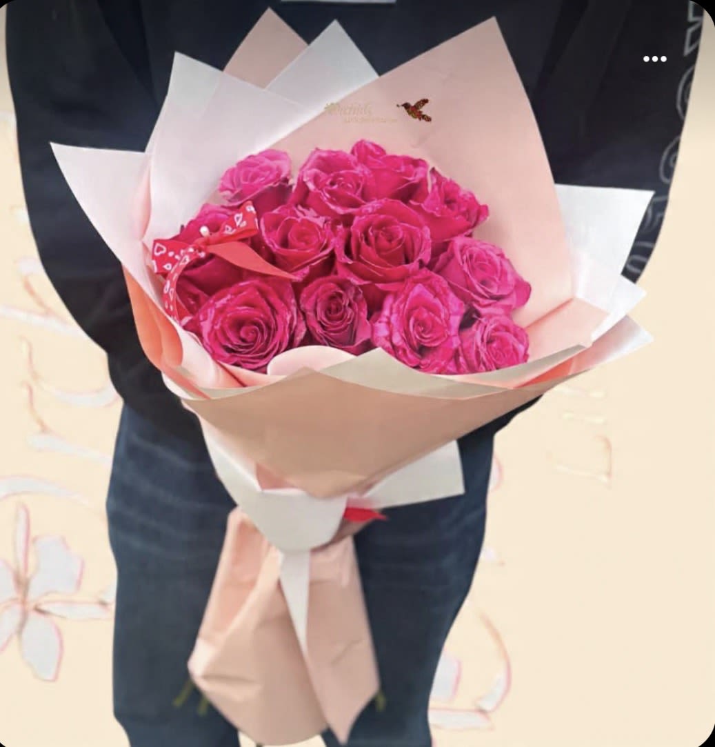 Bouquet of bright pink roses wrapped in pale paper