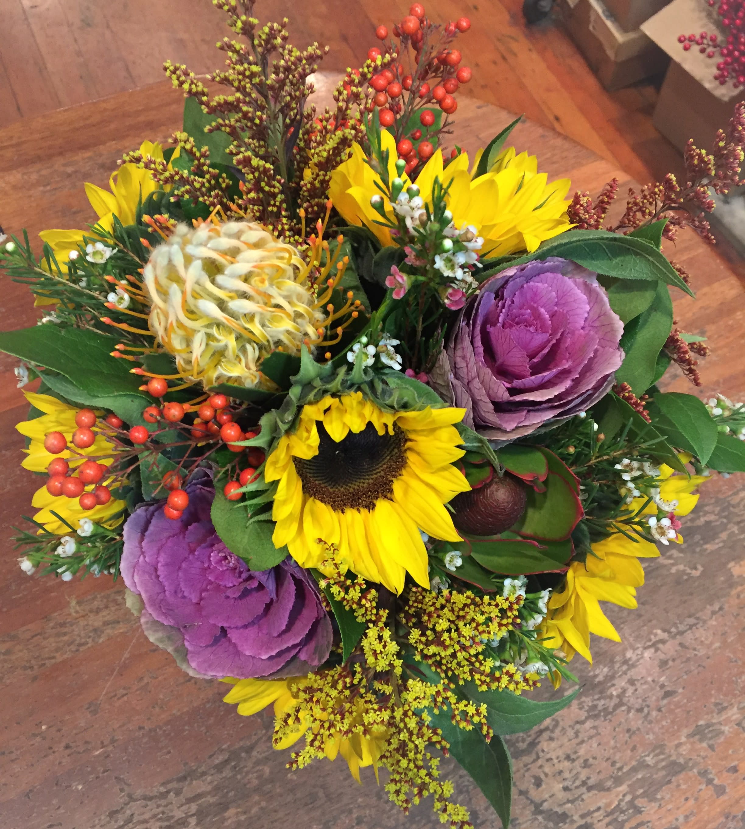 Mixed bouquet with sunflowers, purple ornamental cabbage, and berry accents