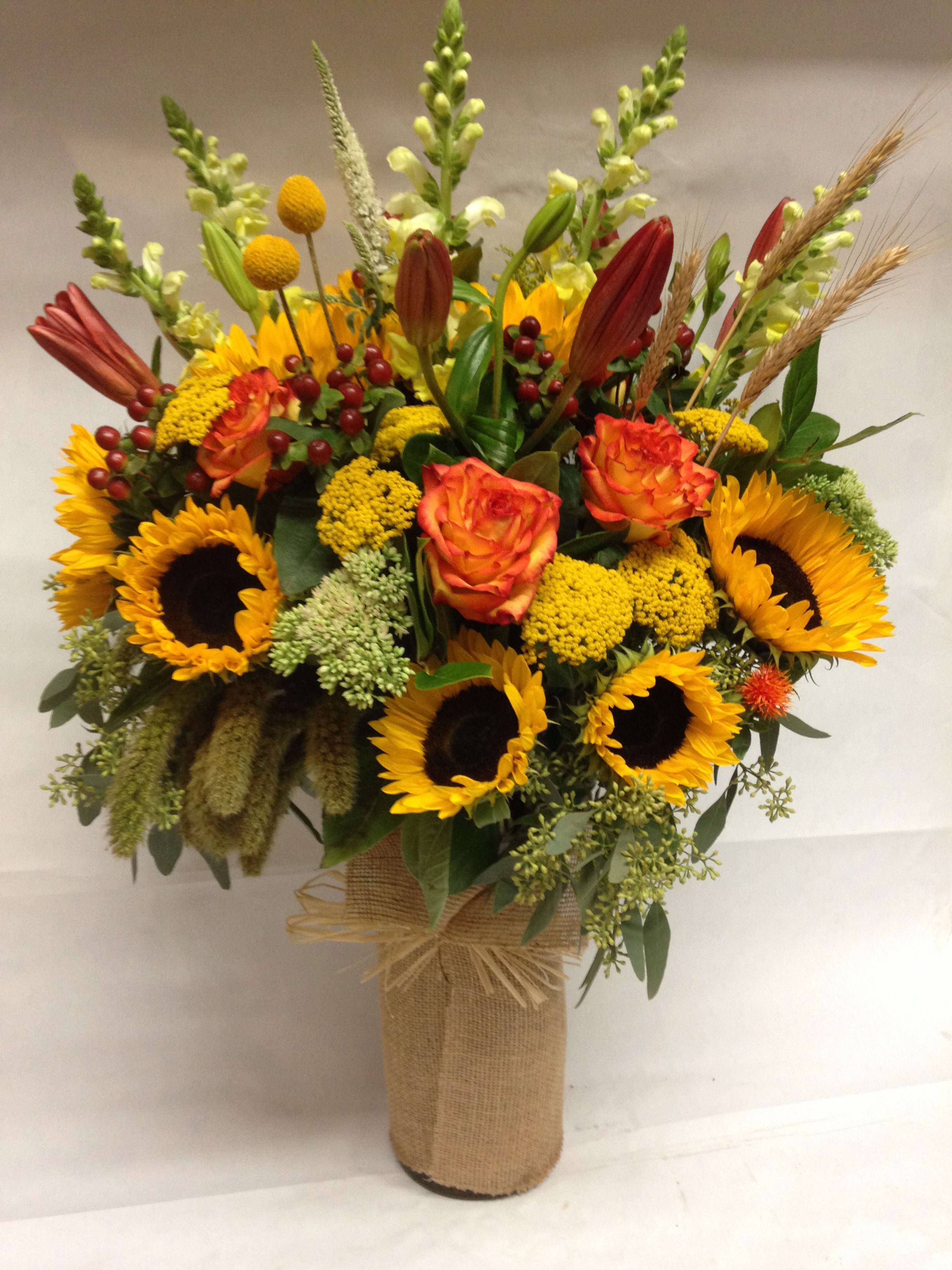 Sunflower and rose arrangement in a burlap-wrapped vase