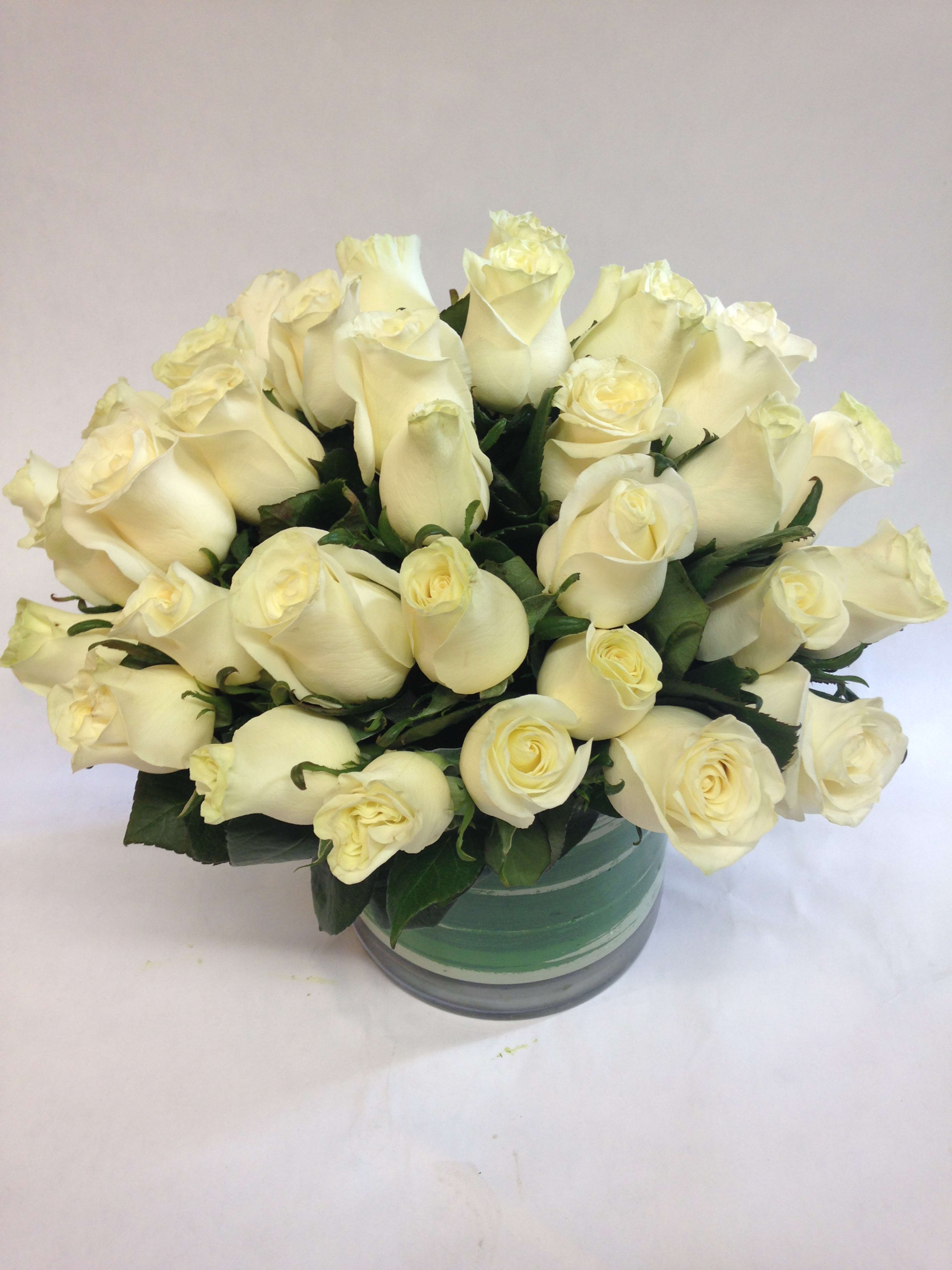 Bouquet of cream white roses in a round glass vase