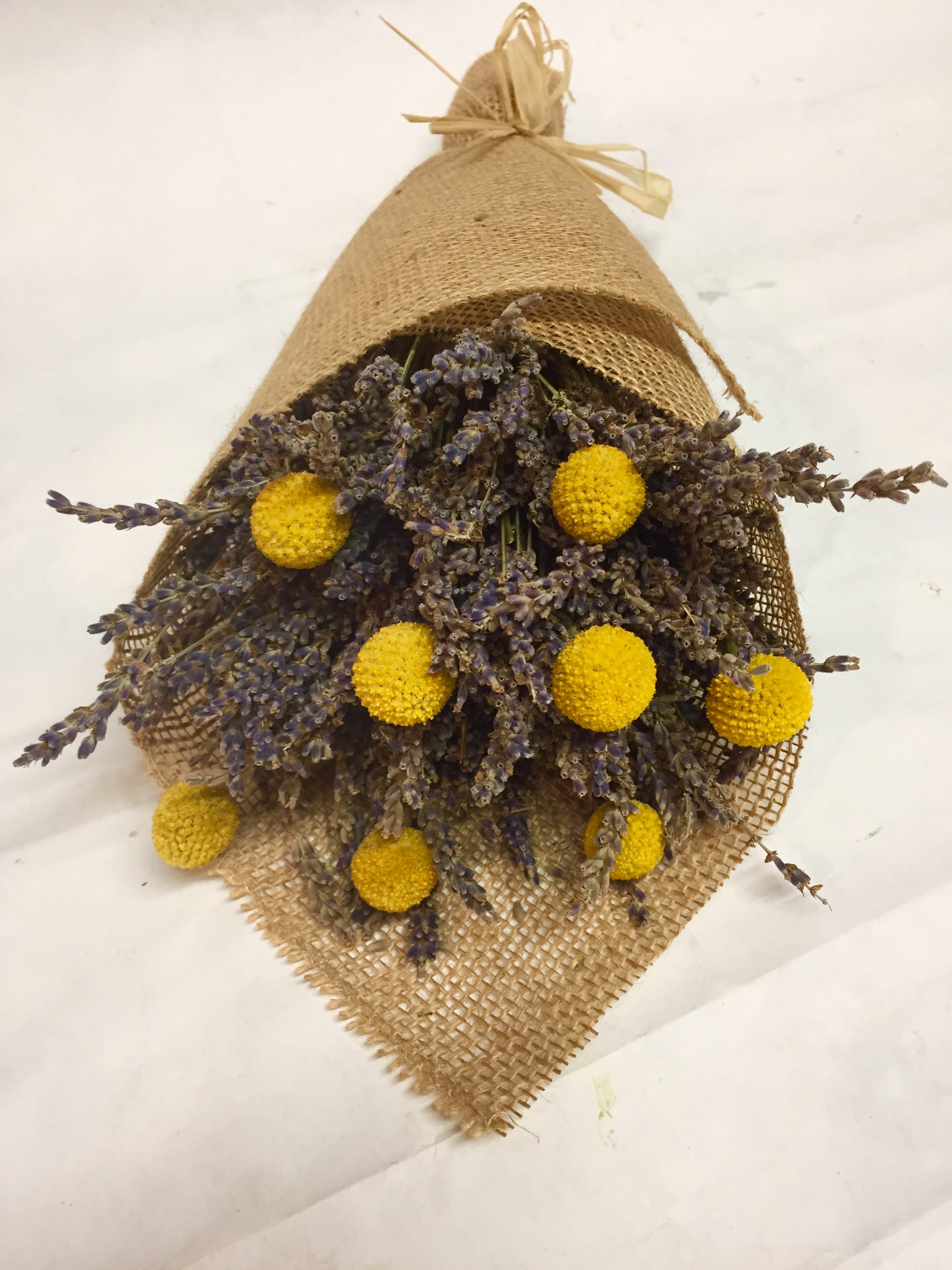 Bundle of dried purple flowers with yellow pom-pom blooms wrapped in burlap