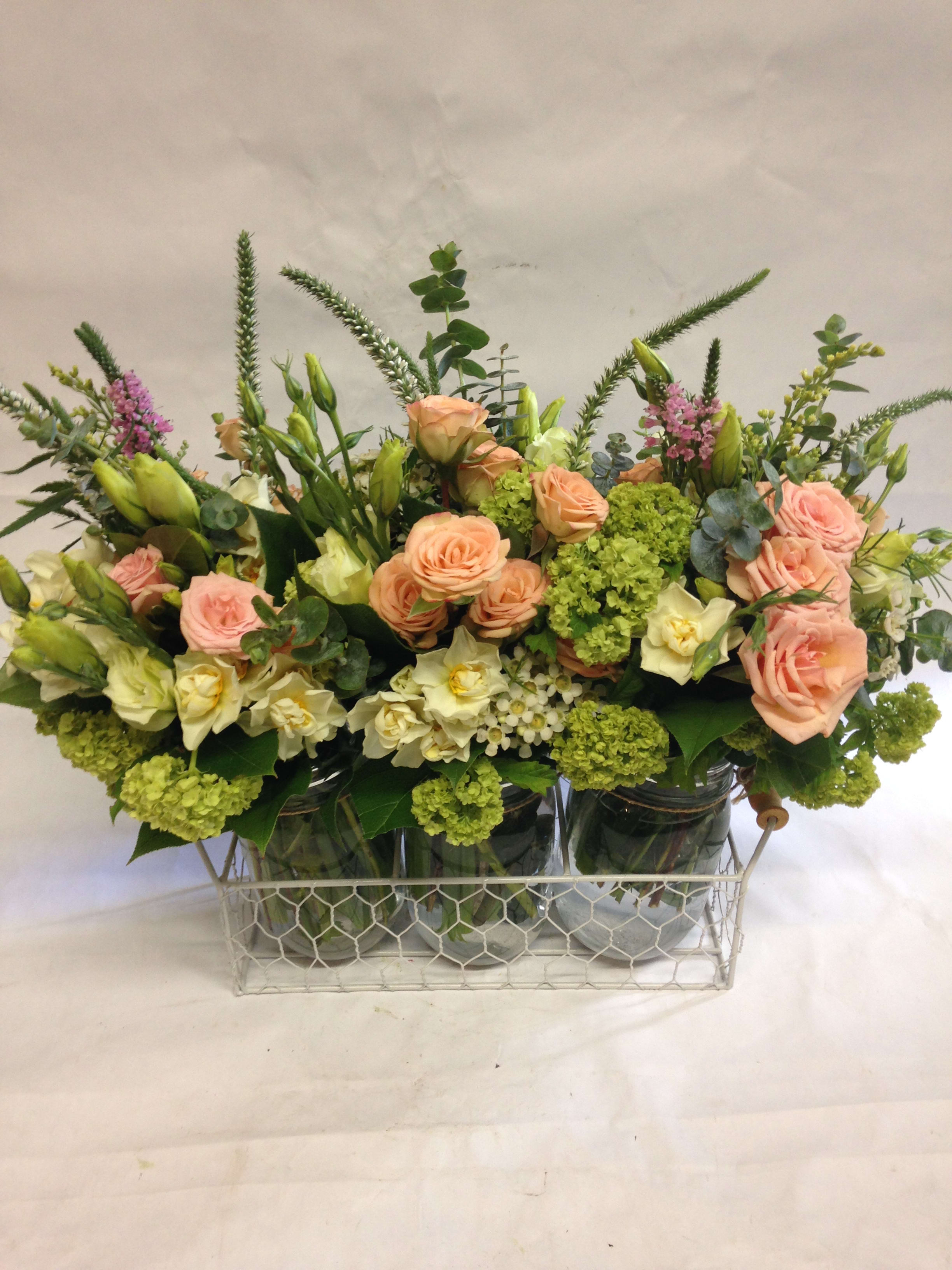 Mixed bouquet of peach roses and white blooms in glass jars