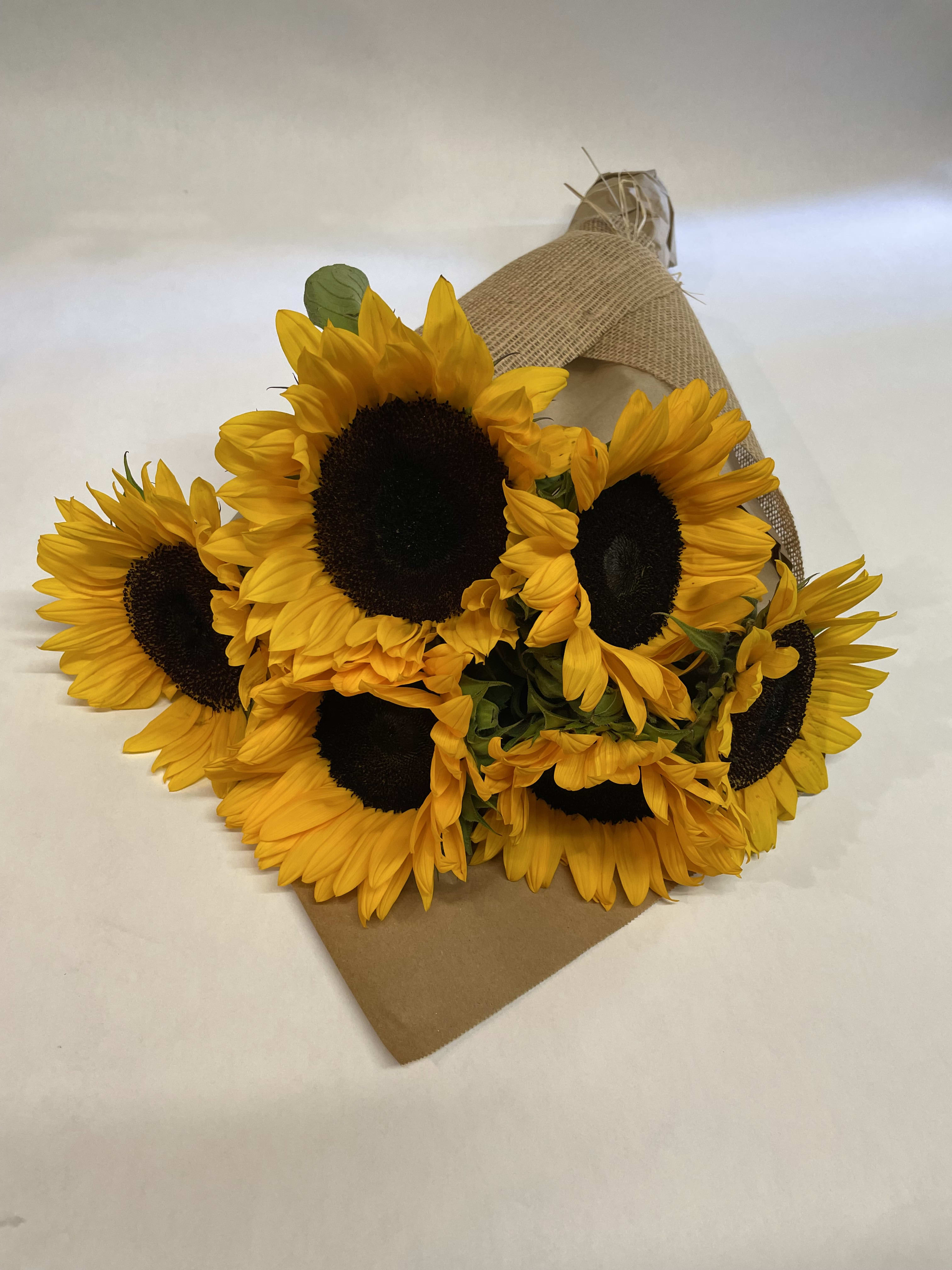 Bouquet of yellow sunflowers wrapped in burlap and kraft paper