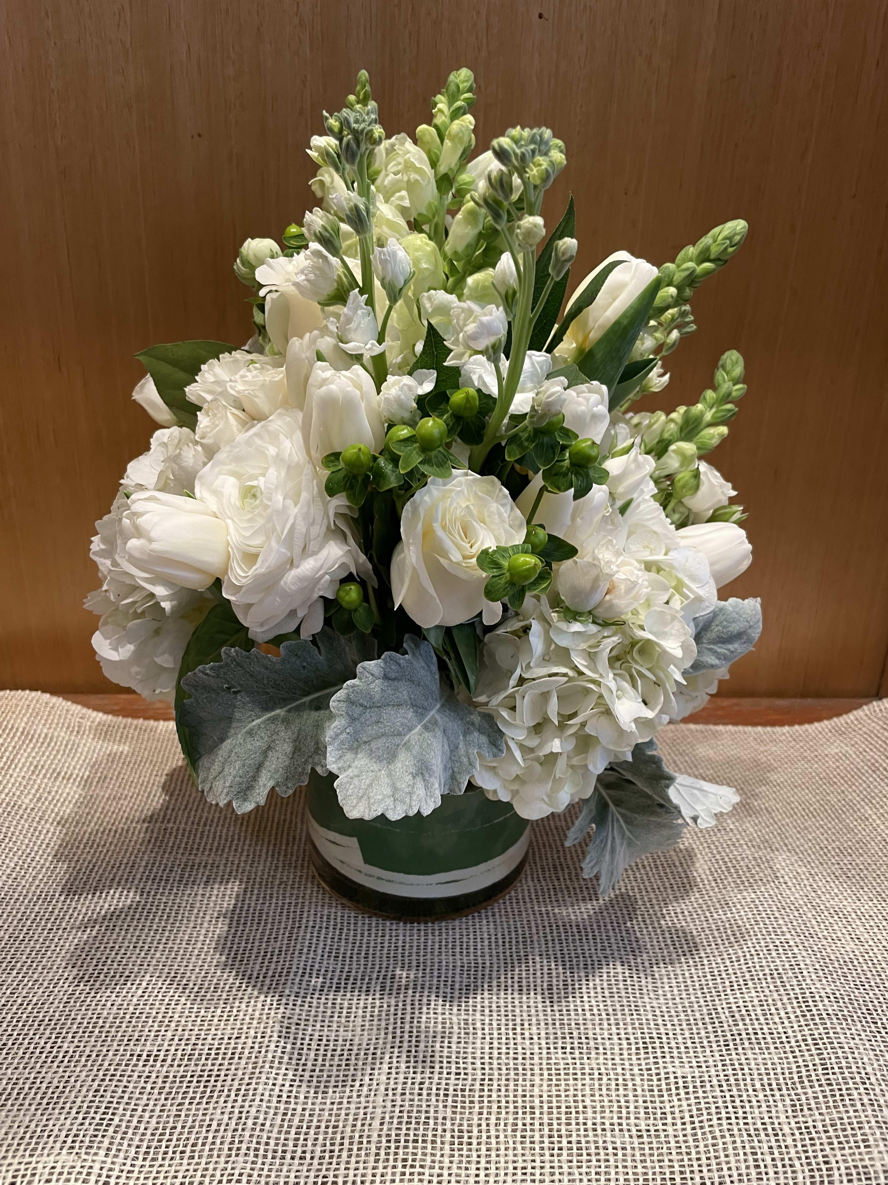 White floral arrangement in a round vase with silvery foliage