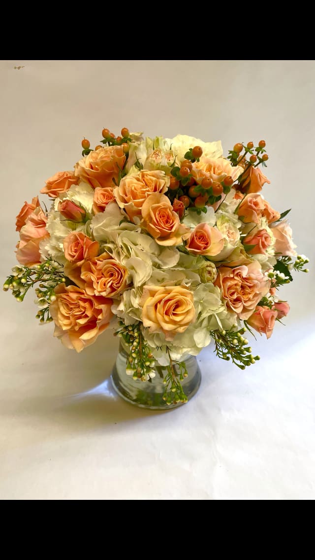 Peach roses and white hydrangeas in a clear glass vase