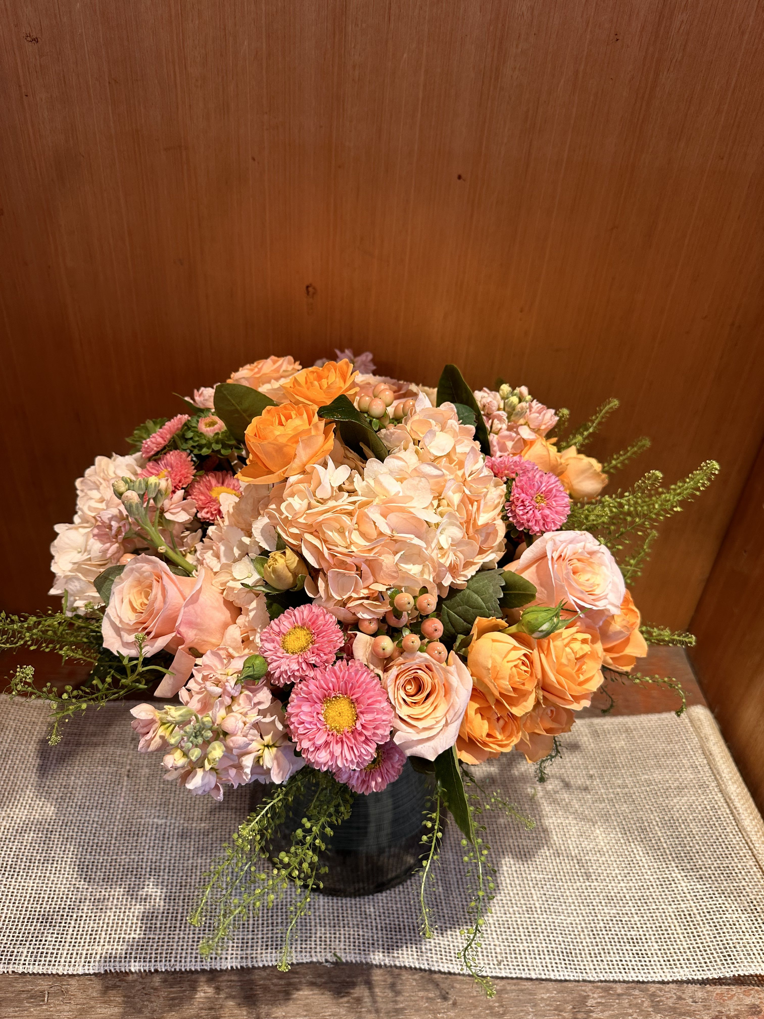 Peach and pink mixed flower arrangement in a dark vase