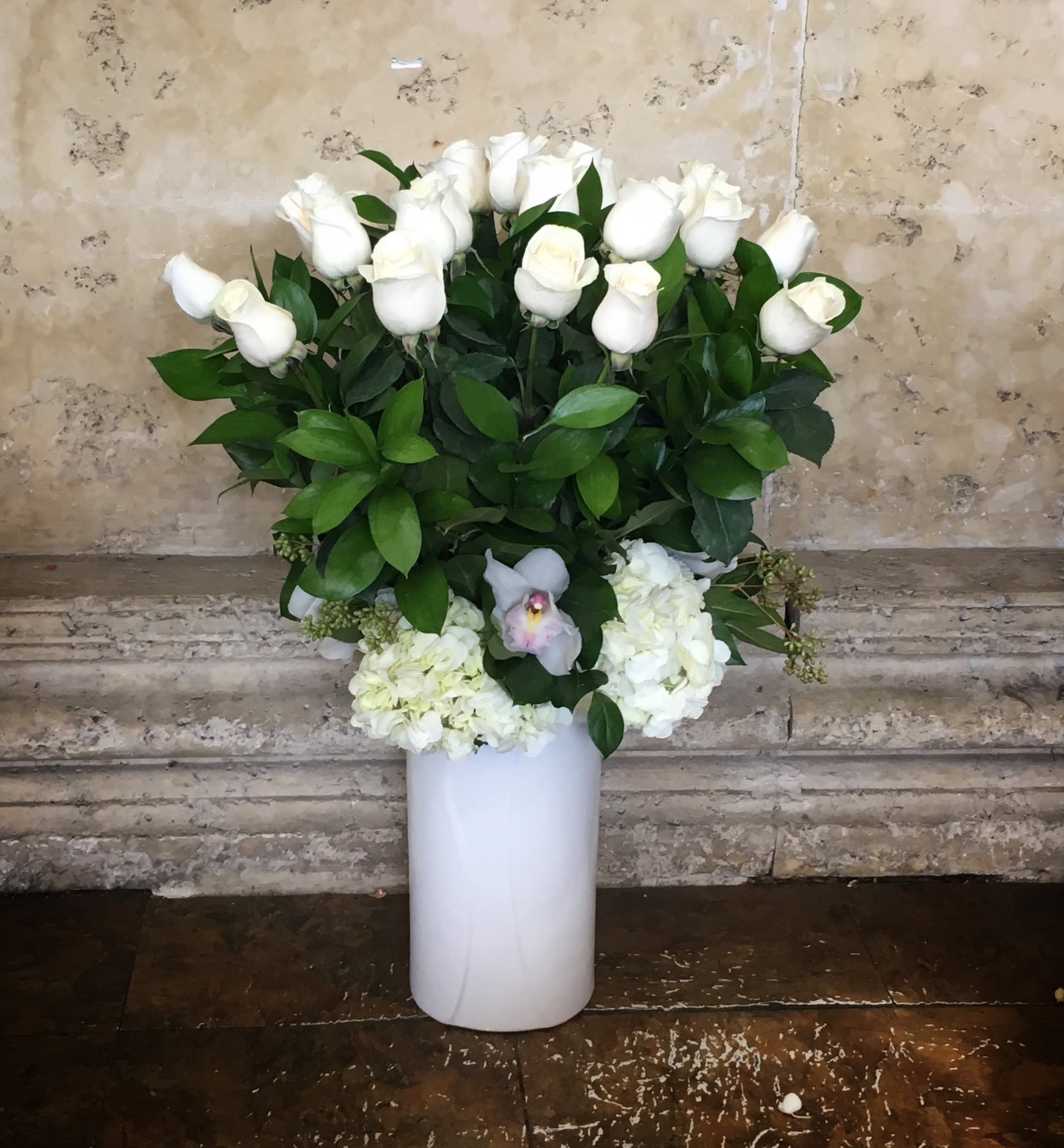 White roses and hydrangeas arranged in a tall white vase