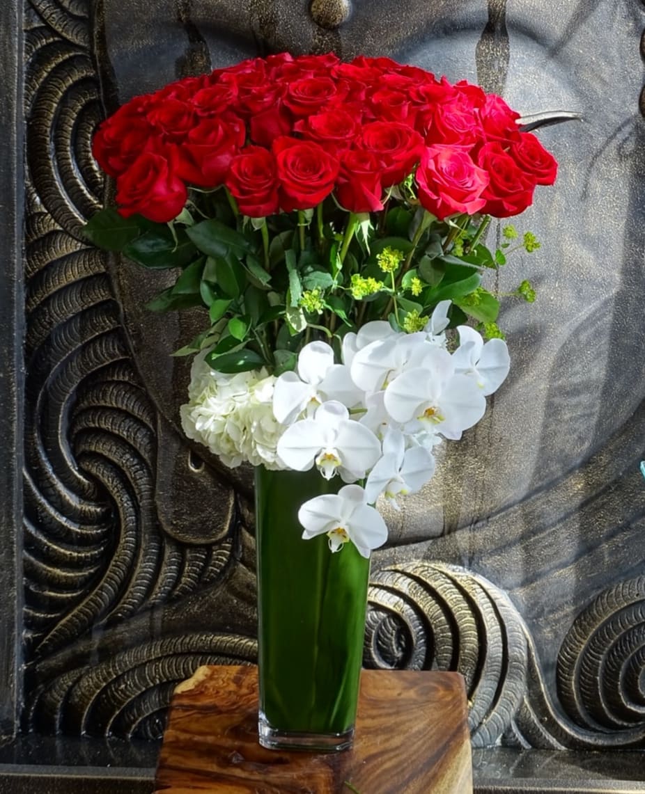 Red roses and white orchids in a tall green vase