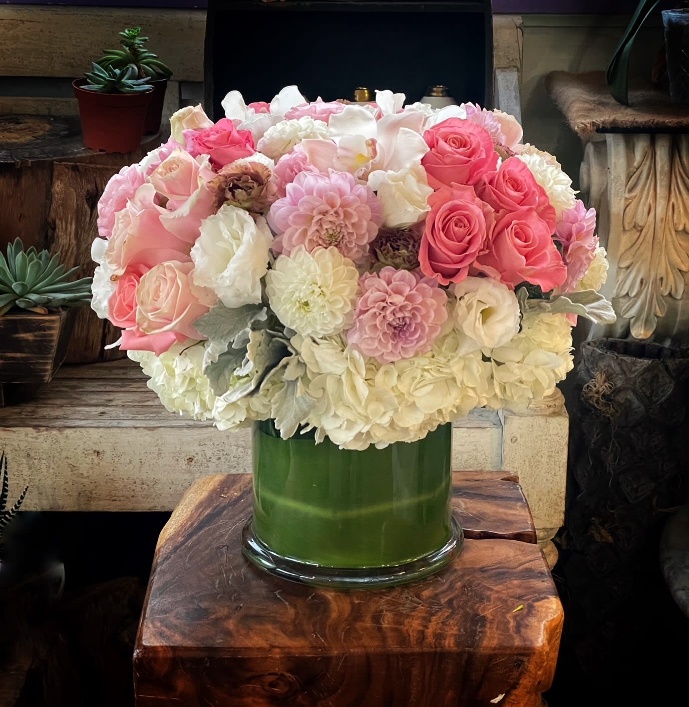 Pink and white flower arrangement in a green glass vase