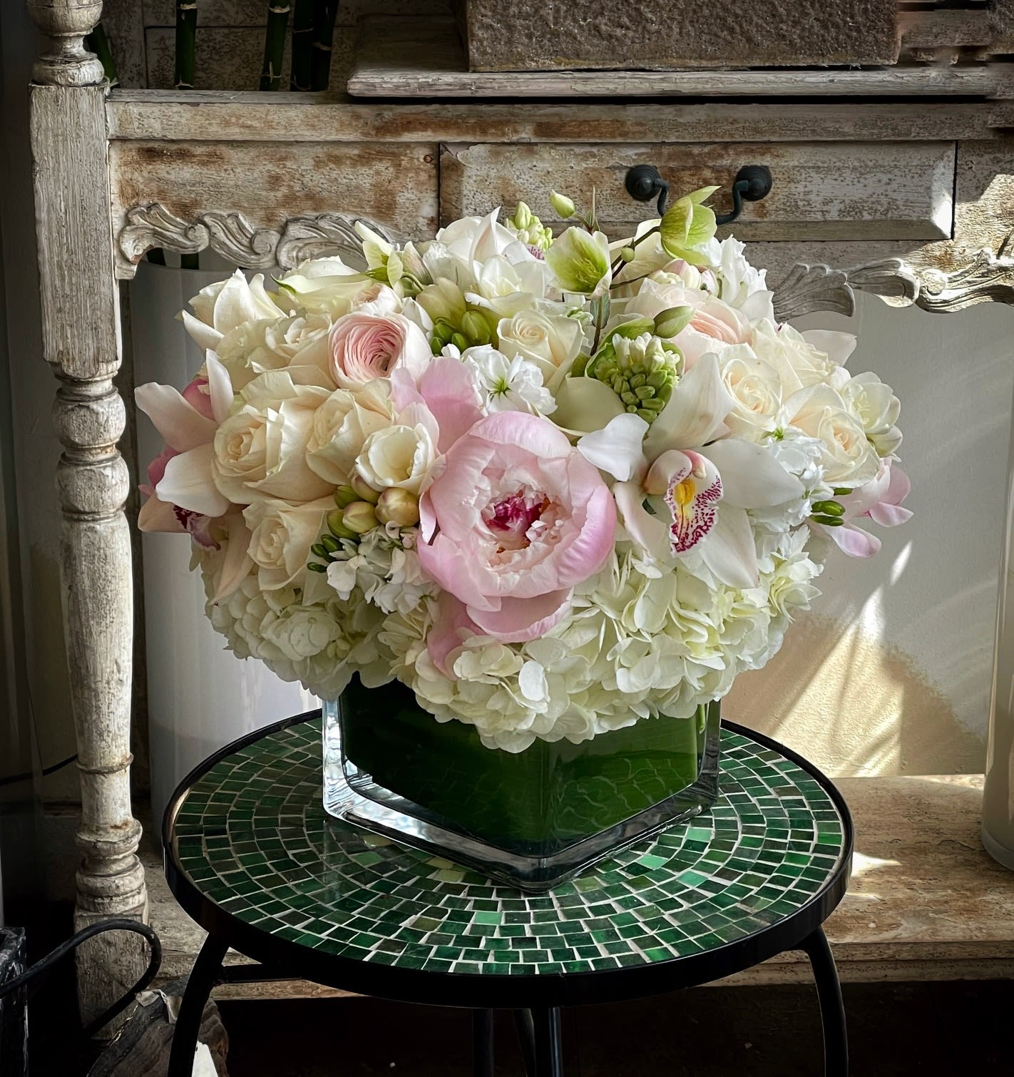 Bouquet of white and blush flowers in a square glass vase