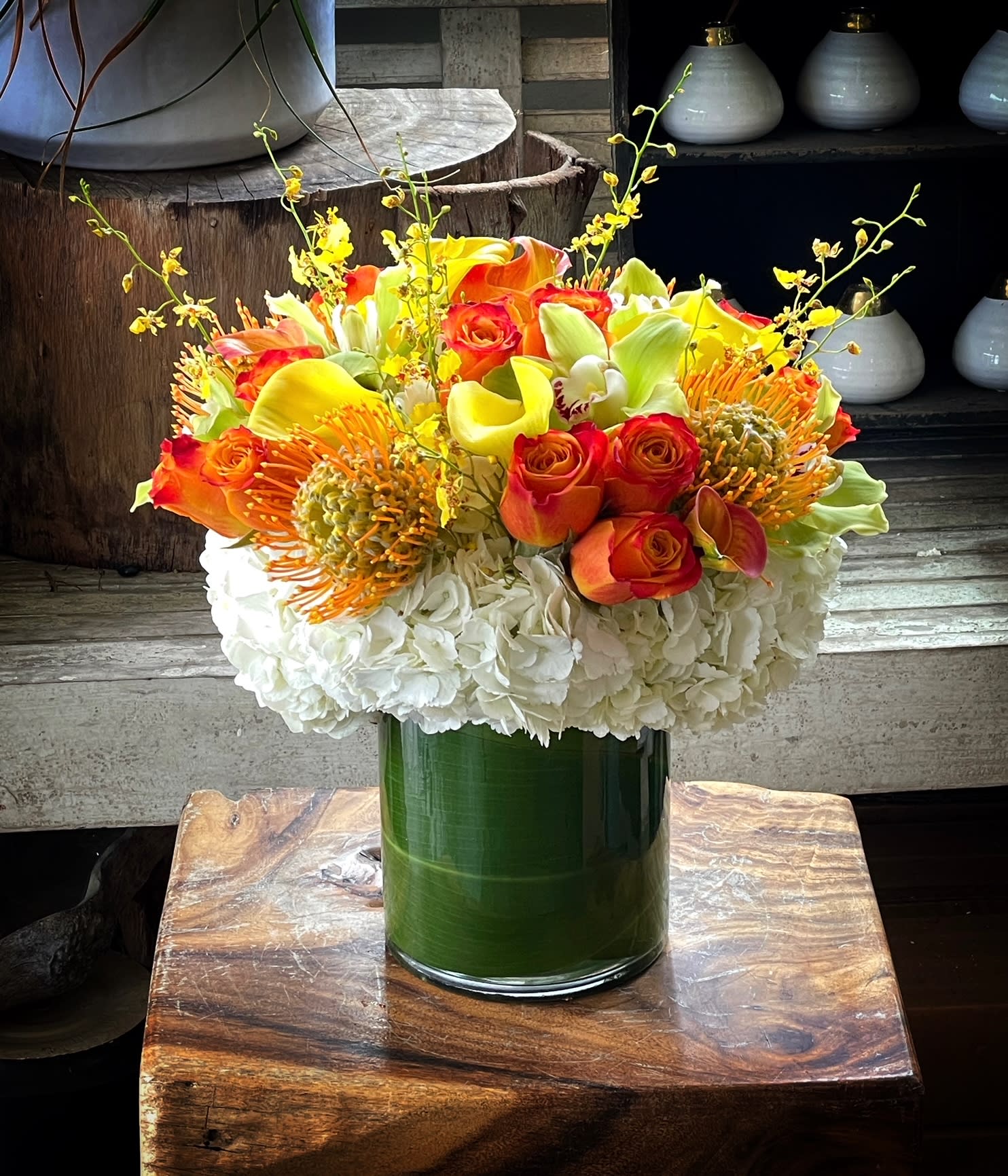 Bouquet of orange and yellow flowers in a green glass vase