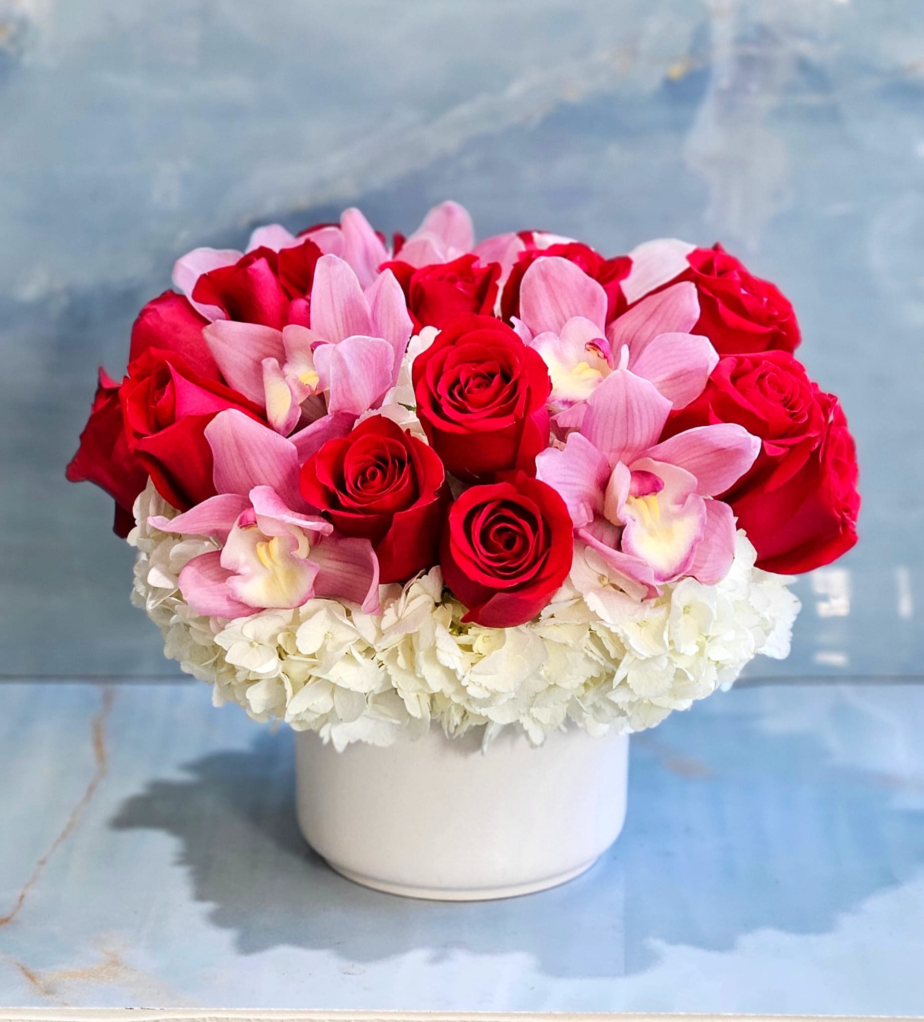 Red roses and pink orchids in a white vase