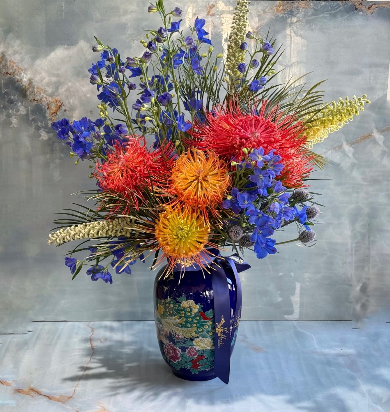 Colorful floral arrangement in a blue vase with a ribbon