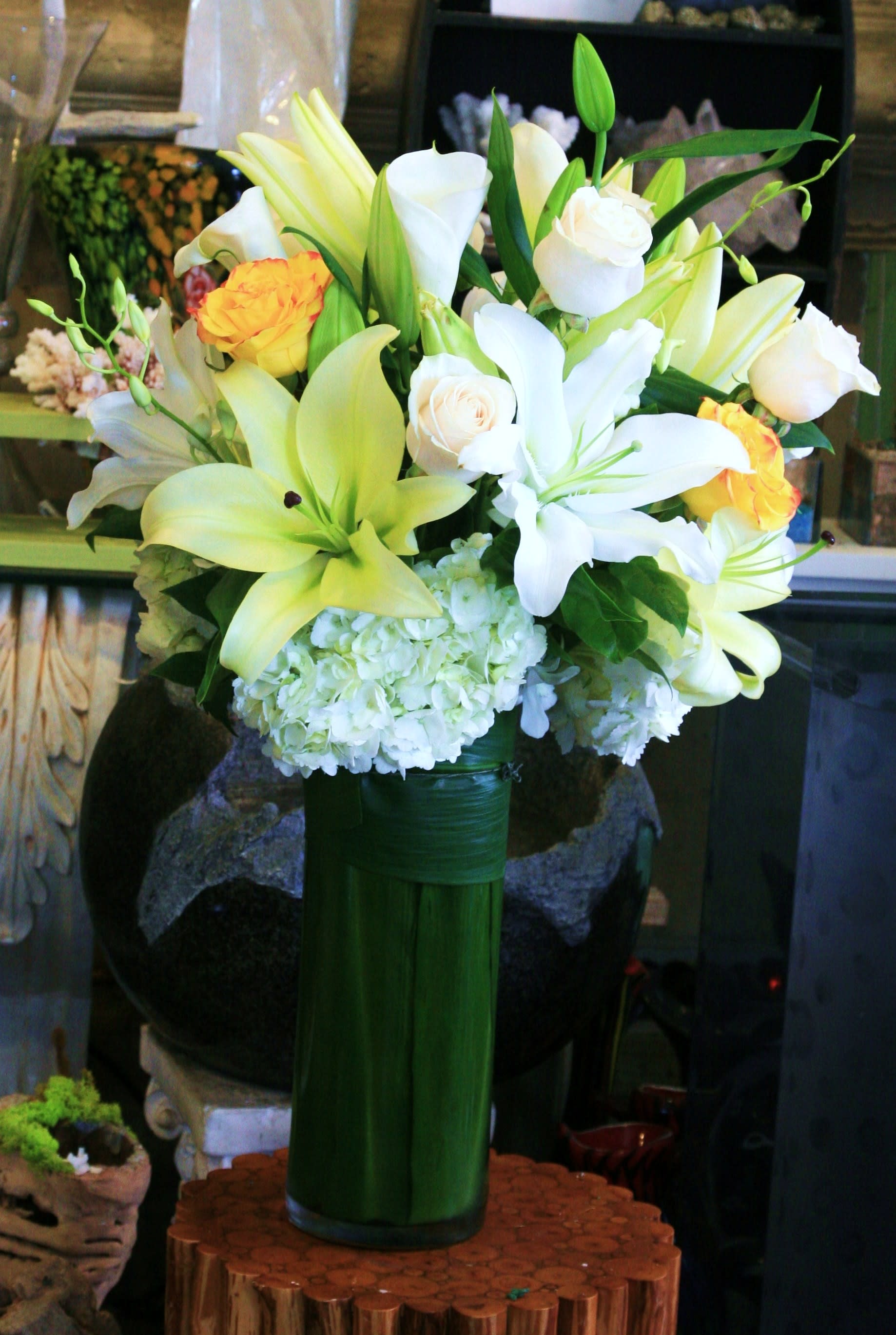Bouquet of white lilies, white roses, and yellow roses in a tall green vase