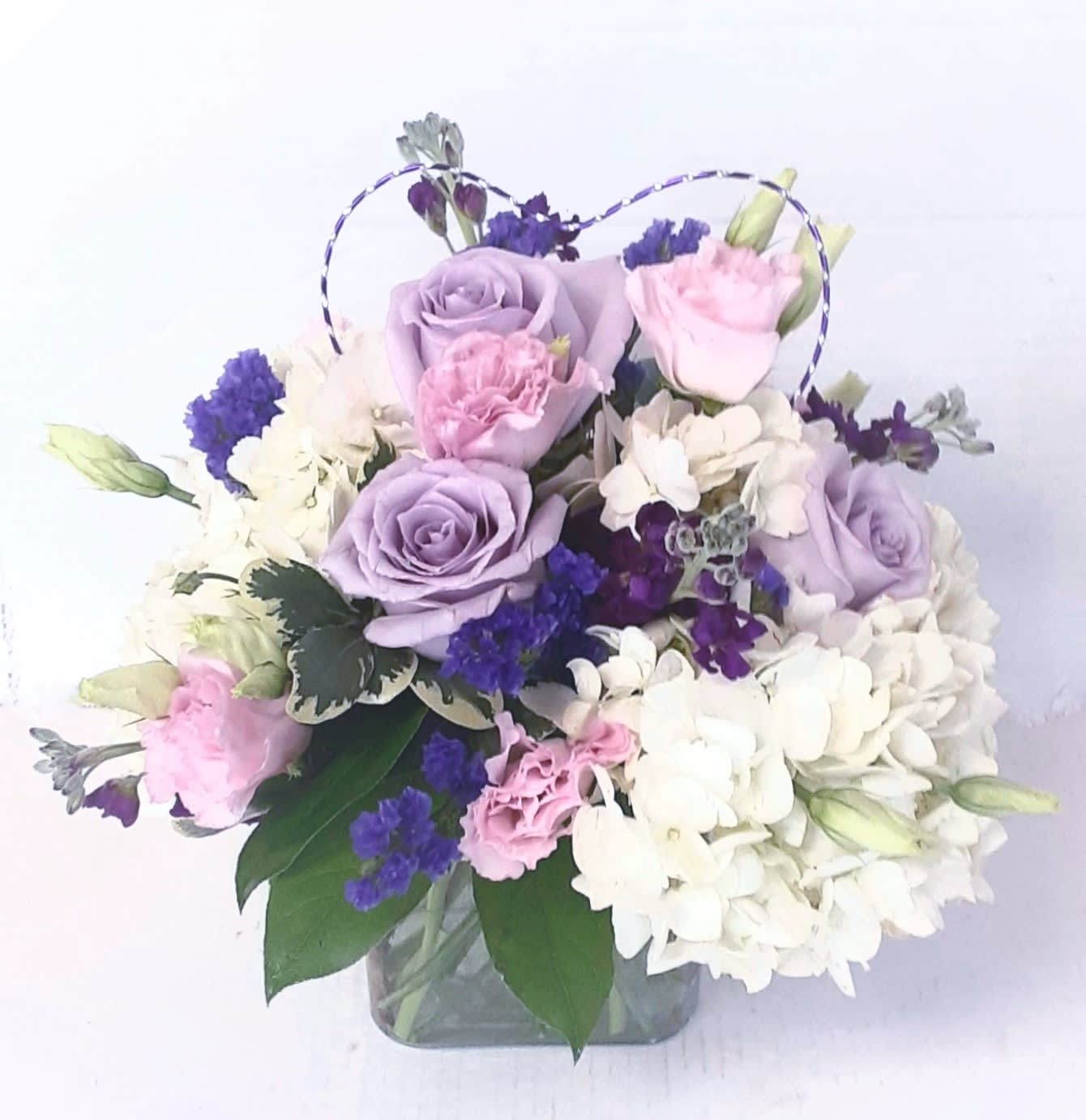 Lavender and pink roses with white hydrangeas in a glass vase