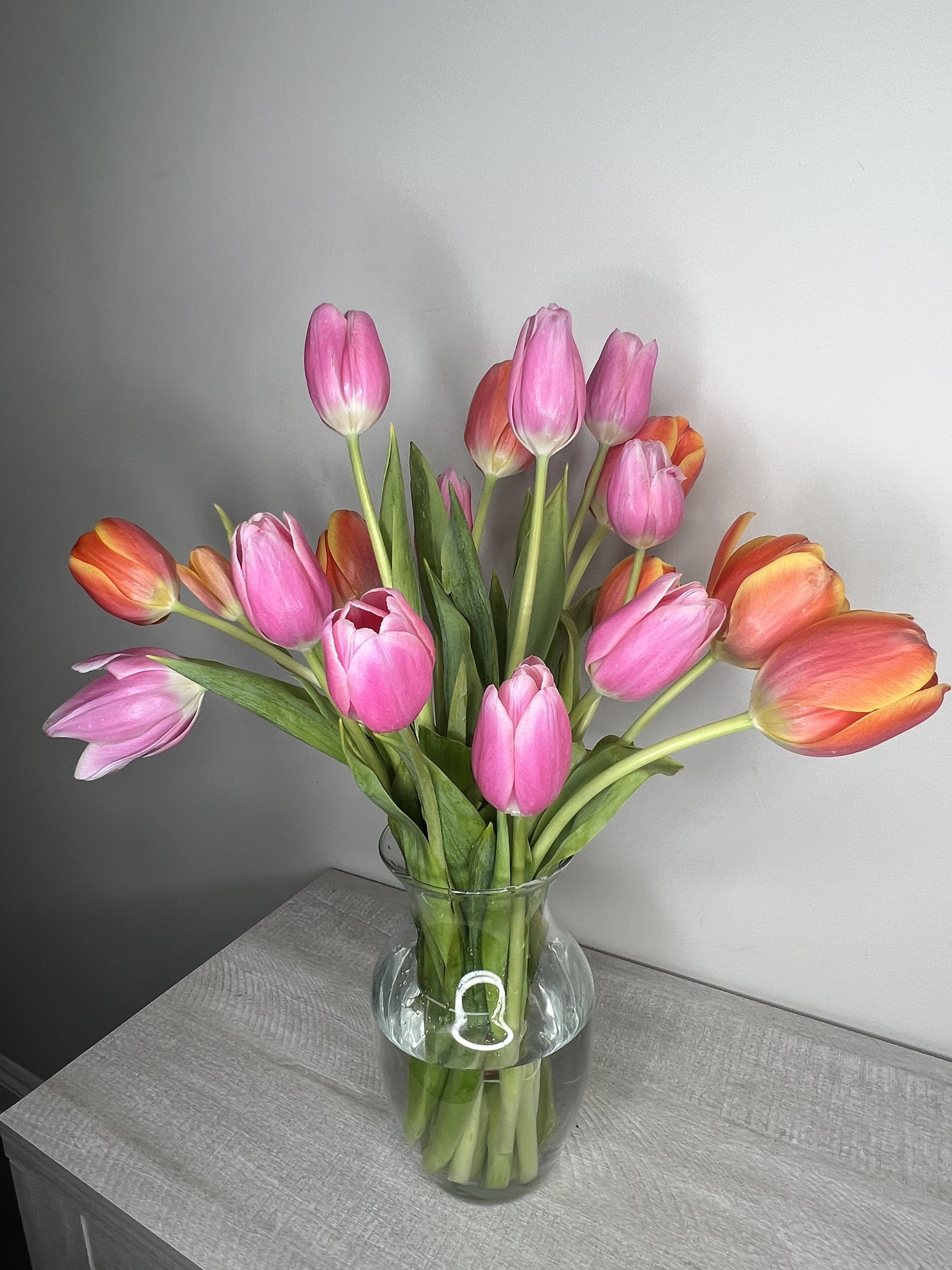 Pink and orange tulips arranged in a clear glass vase